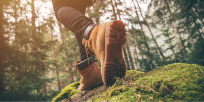 Camel-colour boots walking on moss-covered ground in a woodland environment