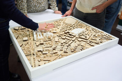 Colour image of a wooden scale plan of a town with an arm/hand hovering over