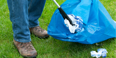 A person putting litter in a refuse bag
